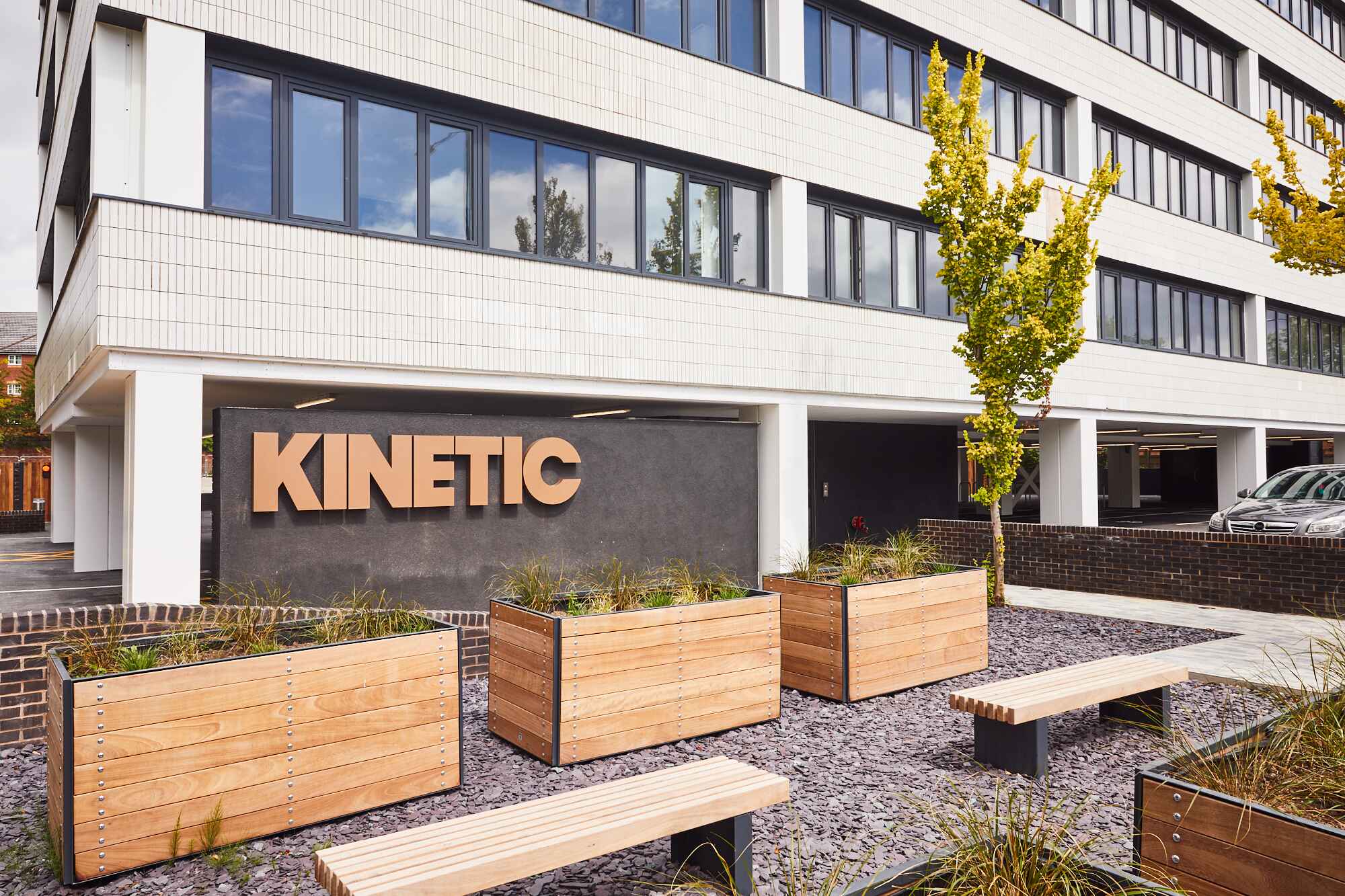 Close-up of the Kinetic apartment building entrance in Old Trafford, Manchester, highlighting the branded signage, slate gravel, and timber planters.