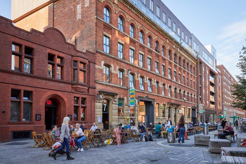 People sitting and walking around Cutting Room Square in Ancoats